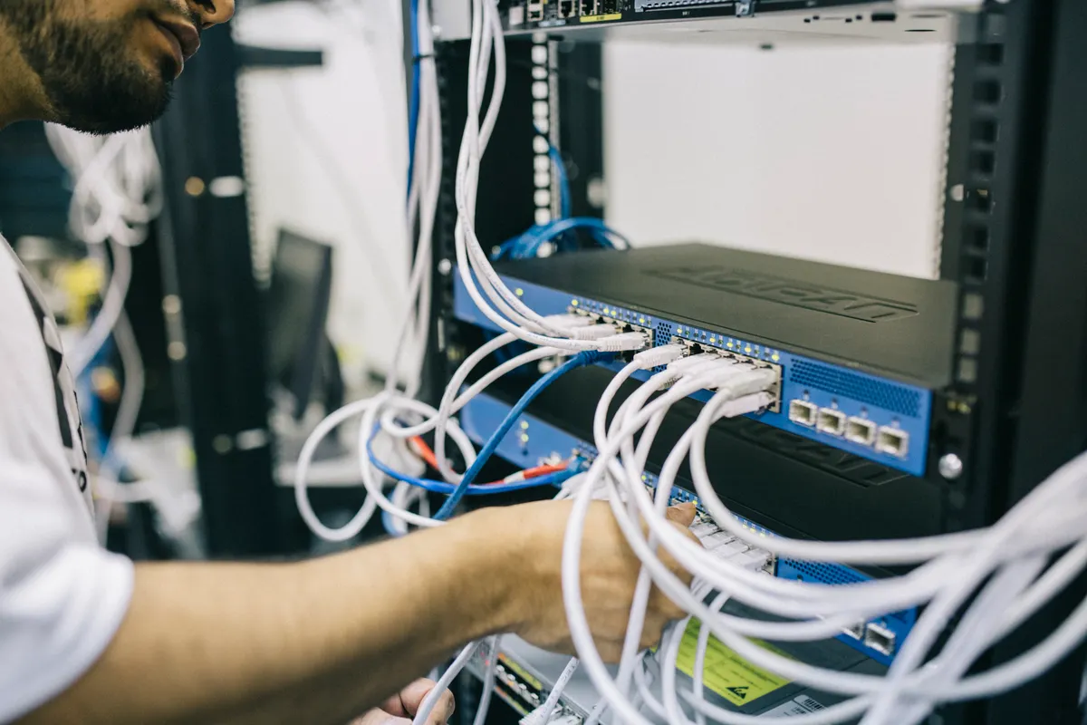 Technician working on cable connections in an equipment rack